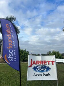 SFSC Foundation flag and Jarrett Ford Avon Park sign in the grass at the driving range.